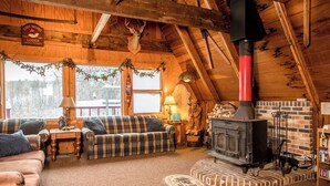 Ein gemütliches Blockhaus-Interieur mit Kamin, Karo-Möbeln und Holzbalkendecke.
