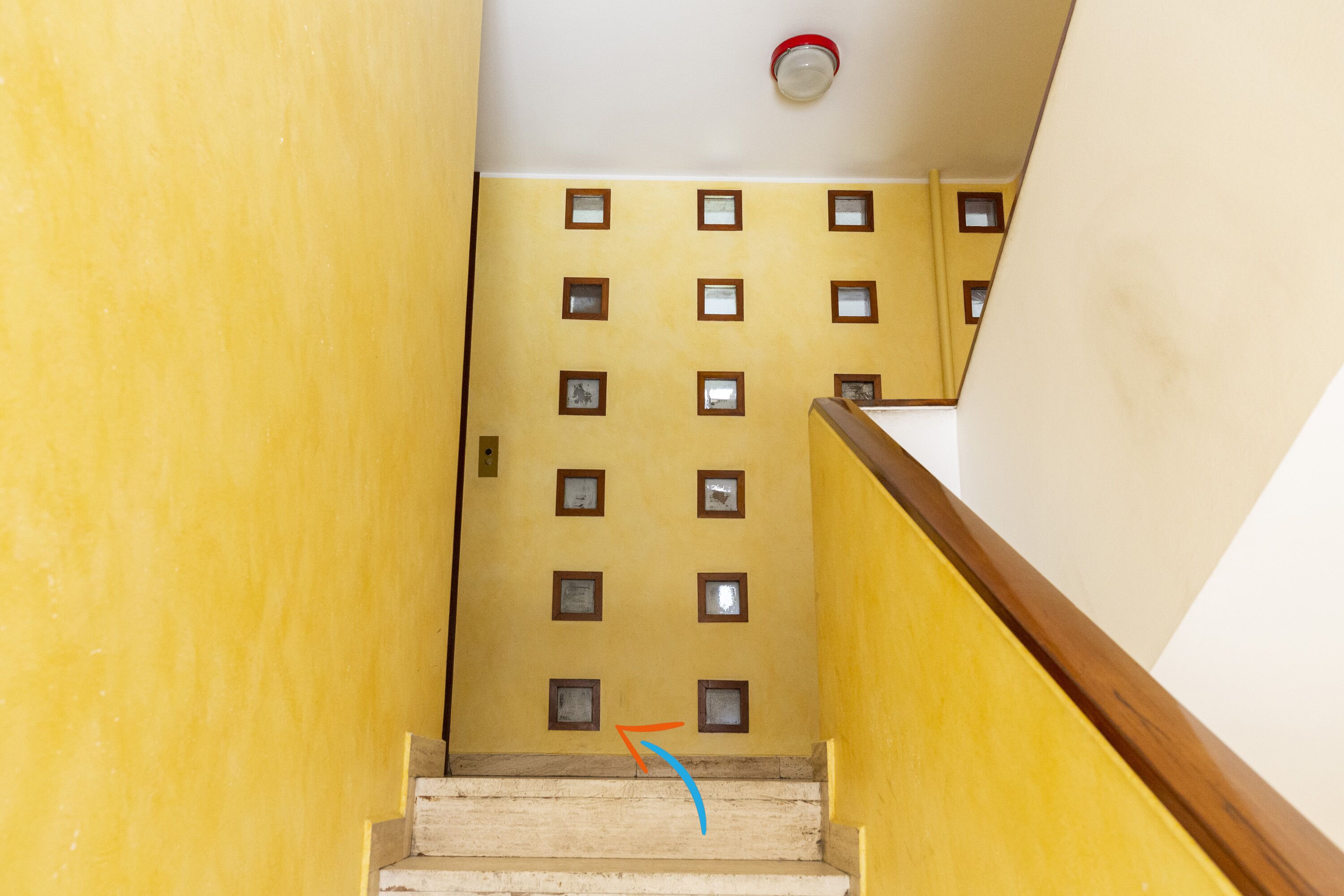 Un escalier avec un mur jaune et une rampe en bois.