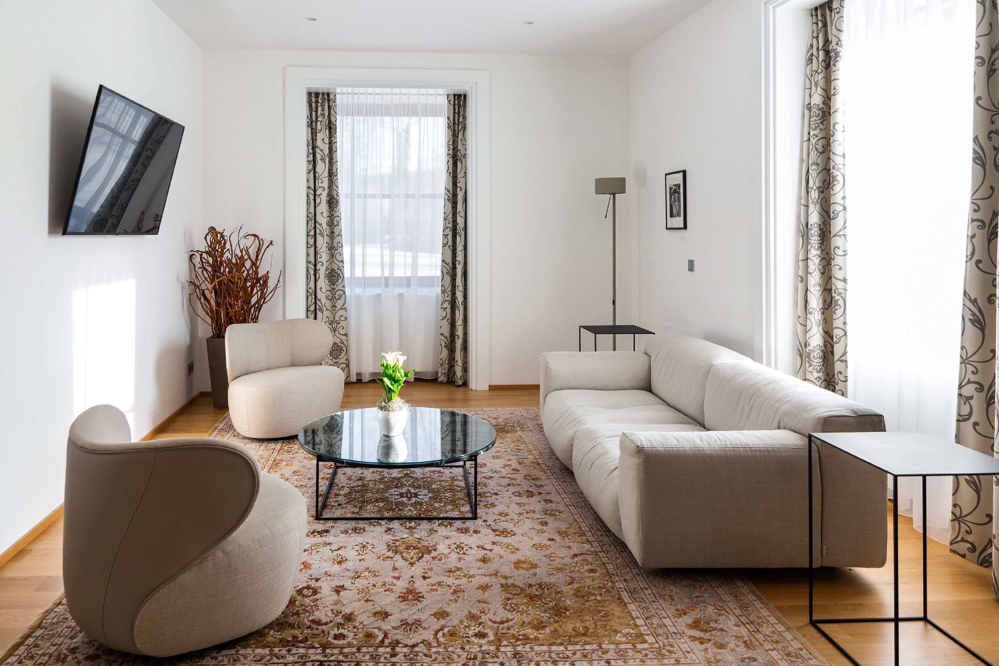 A modern living room with a sofa, a round coffee table, and a TV mounted on the wall.