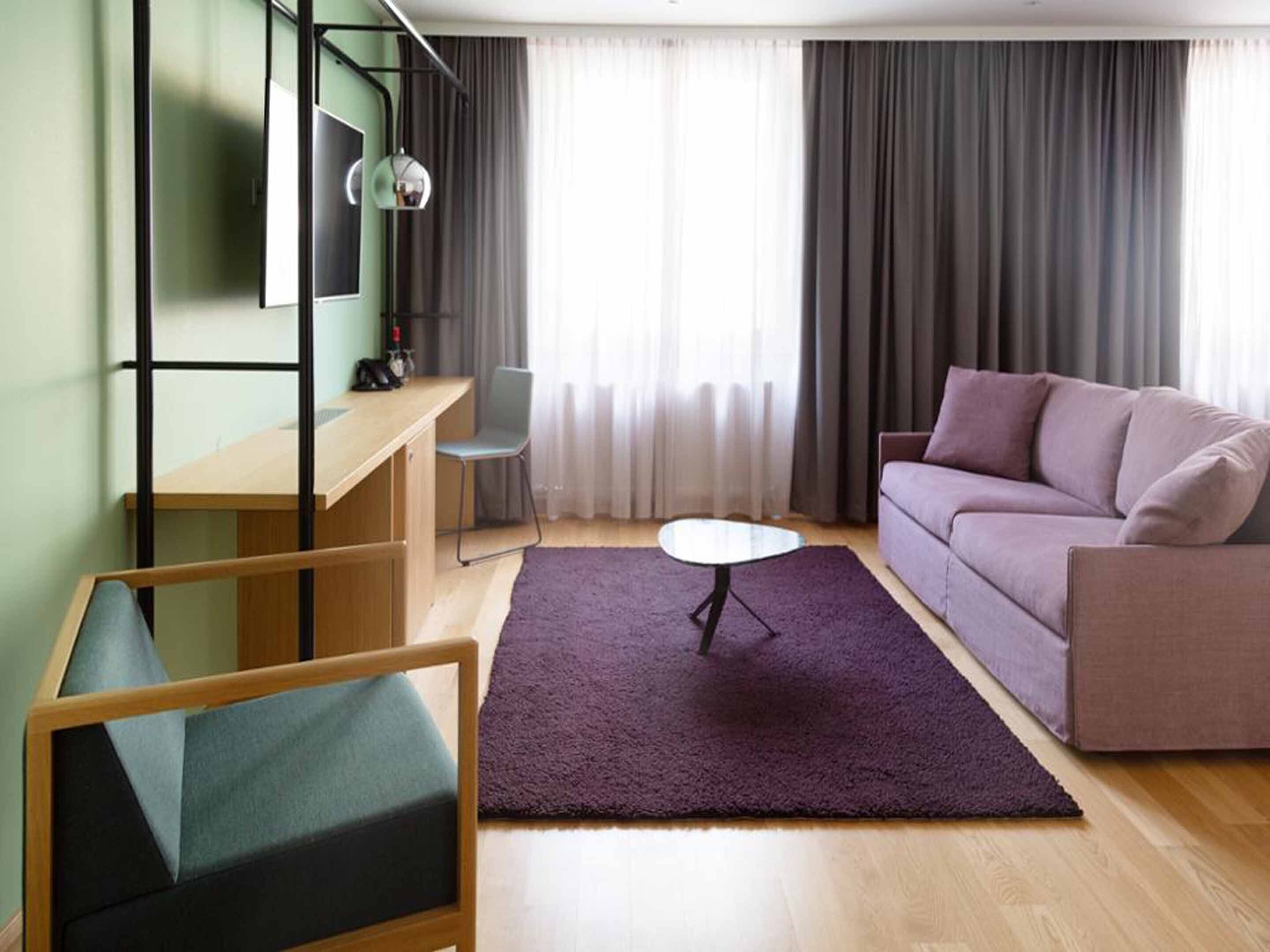 Ein modernes Wohnzimmer mit einem Holztisch, einem violetten Sofa und einem kleinen runden Tisch.