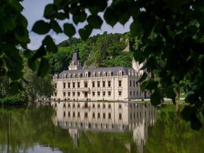 A large, historic building with a symmetrical facade, a prominent tower, and a reflection in the water.