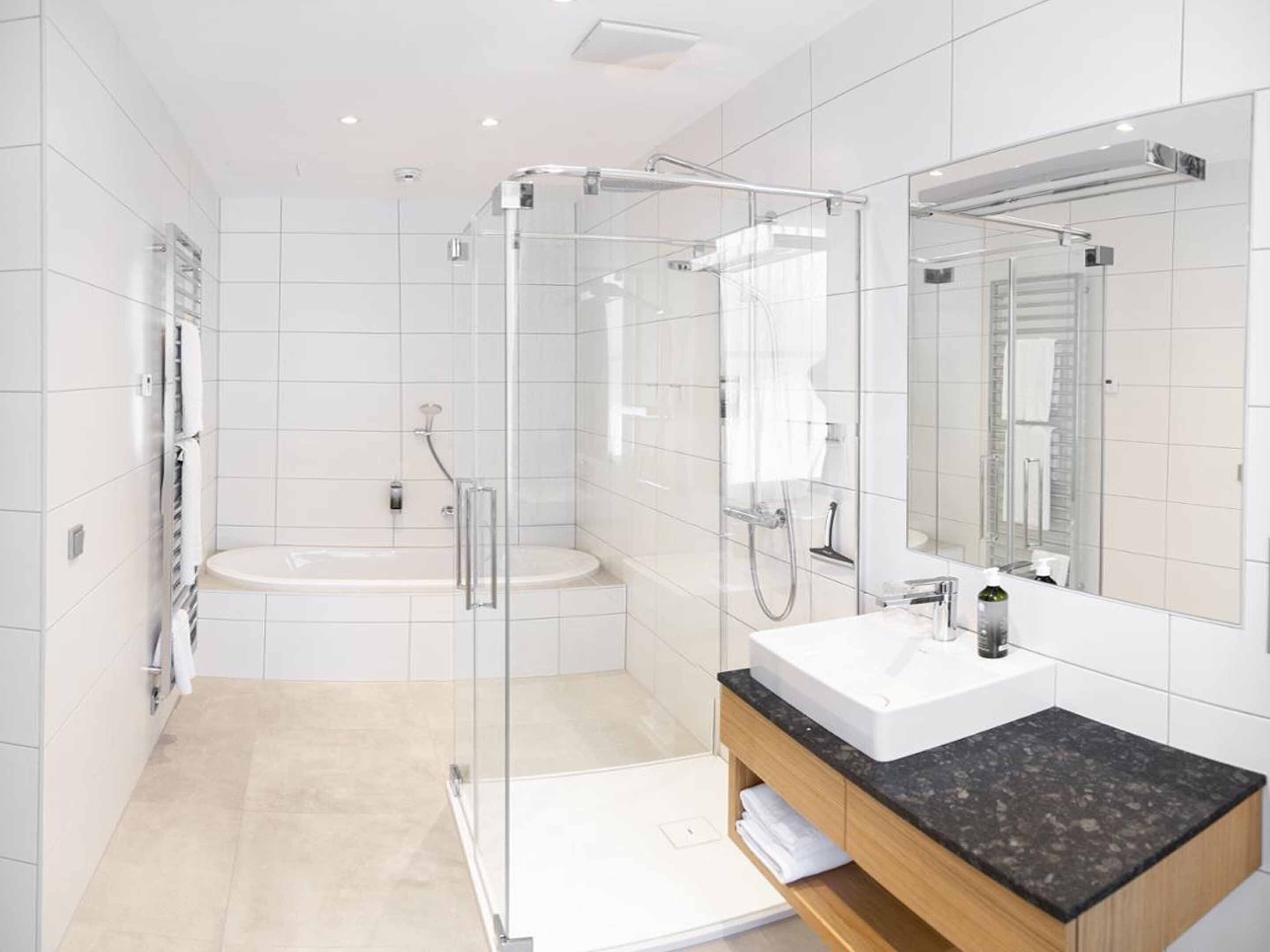 A modern bathroom with a glass-enclosed shower, a freestanding bathtub, and a vanity with a black countertop.