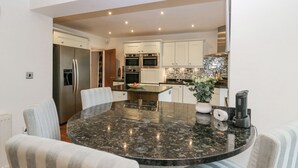 Een moderne keuken met witte kastjes, roestvrijstalen apparatuur en een marmeren eiland.