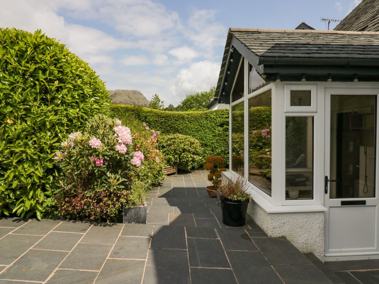 Een tuinpad dat leidt naar een wit huis met een pannendak en een glazen deur.