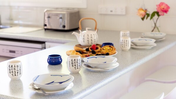 A kitchen counter with a toaster, a teapot, and various dishes and utensils. - Maxi's – pet friendly, walk to beach, EV charger (Culburra Beach)