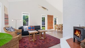 Una sala de estar moderna con chimenea, un sofá, una mesa de comedor y un amplio ventanal.