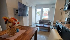 Ett modernt kök med en matplats, en soffa och en tv som är monterad på väggen.
