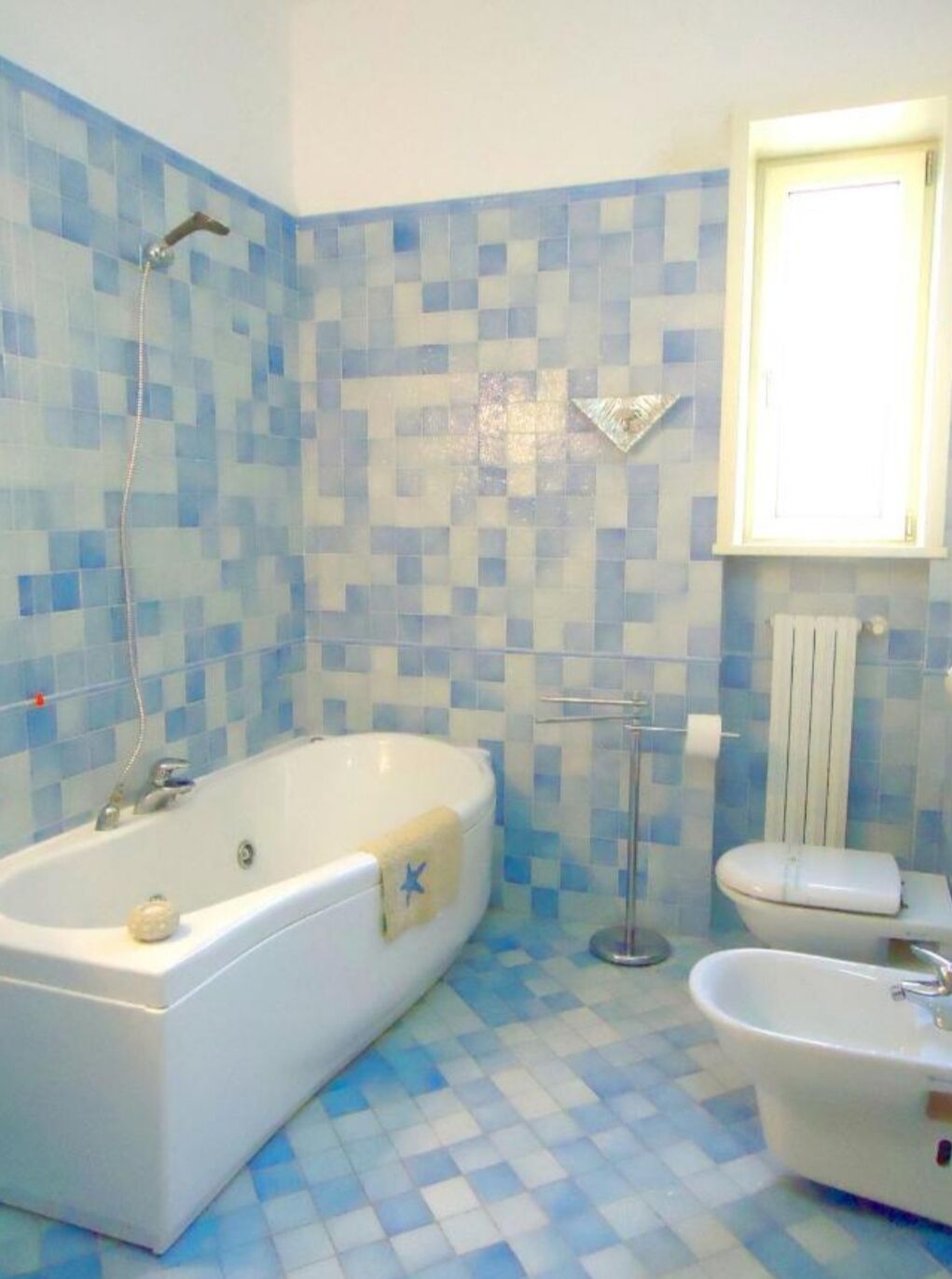A bathroom with a bathtub, a toilet, and a sink. The walls are tiled with blue and white tiles.
