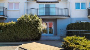 A multi-story residential building with balconies, a central entrance, and surrounding greenery. - Comfortable Studio in Puck | Parking and 400 m to the Beach (Puck)