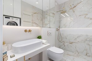 A modern bathroom with a large white sink, a toilet, and a shower area.