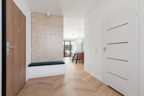 Ein Flur mit einer hölzernen Bank, einem weißen Kleiderschrank und einem Essbereich im Hintergrund.