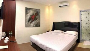Een hotelkamer met een groot bed, een bureau met stoel, een schilderij aan de muur en een airconditioner.