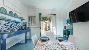 Una cocina con azulejos azules y blancos, una mesa de comedor con platos y un televisor montado en la pared.