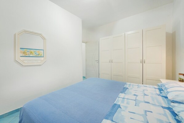 A bedroom with a bed, a wardrobe, and a framed picture on the wall. - House with Private Courtyard 200 m from the Cliffs (Procida)