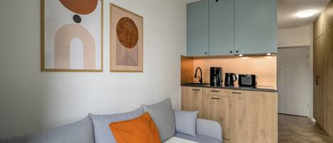 Un salón moderno con sofá gris, cojín naranja y armarios de madera.