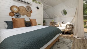 A cozy bedroom with a large bed, a small table, and a chair. - Glamping Dome · Hot Tub, Fire Pit & Forest Views (Simpson)