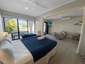 A hotel room with two beds, a sofa, a dining table, and a TV. - Beachside Palms Unit 3 (Nelly Bay)