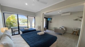 A hotel room with two beds, a sofa, a dining table, and a TV.