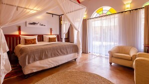 Ein Schlafzimmer mit einem großen Bett, einer Sitzecke mit einem Sessel und einem Himmelsbett.