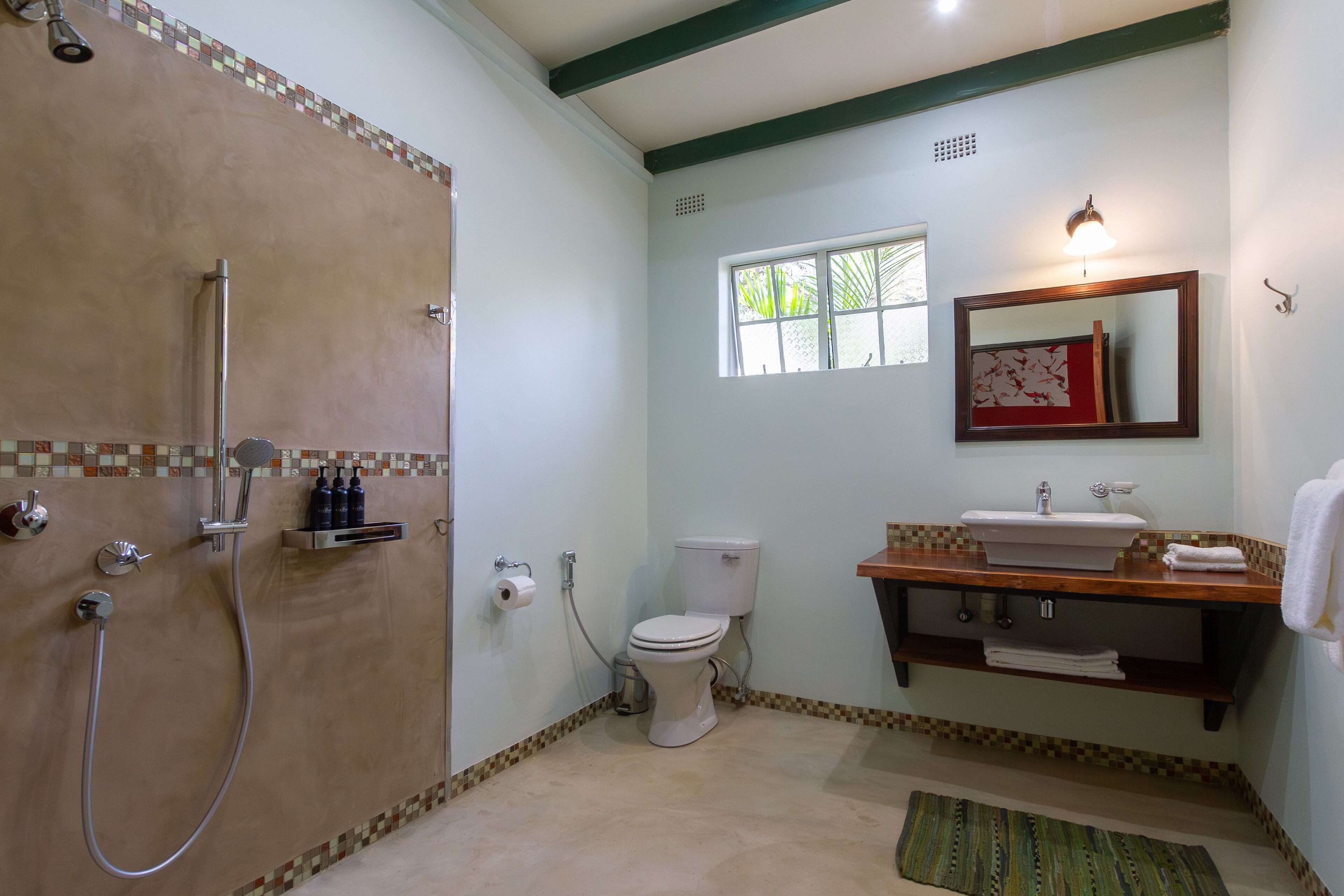 A bathroom with a shower, toilet, sink, and a window.