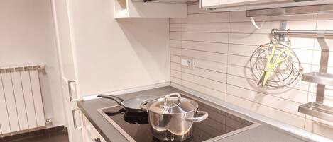 Una cocina con estufa, olla y sartén.