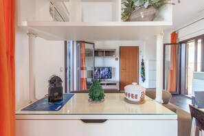 Relax in this stylish living room with a glass-top coffee table, television, and large window.