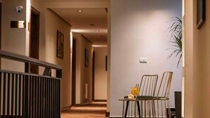 A hotel hallway with a railing, a table with chairs, and a potted plant. - Monarch Hotel (Prizren)
