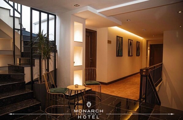Un vestíbulo de hotel con una escalera, zona de estar y obras de arte enmarcadas en las paredes.