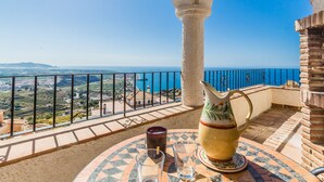 A balcony with a clear view of the sea and landscape, a tiled table with a pitcher and glasses, and a decorative metal railing. - Villa with private pool and amazing views (Salobreña)