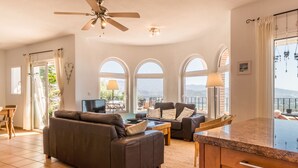 A spacious living room with a sofa, a coffee table, and a TV. There are large windows with a view of the outdoors. - Villa with private pool and amazing views (Salobreña)