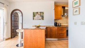 A kitchen with wooden cabinets, a marble countertop, and a fruit bowl. - Villa with private pool and amazing views (Salobreña)