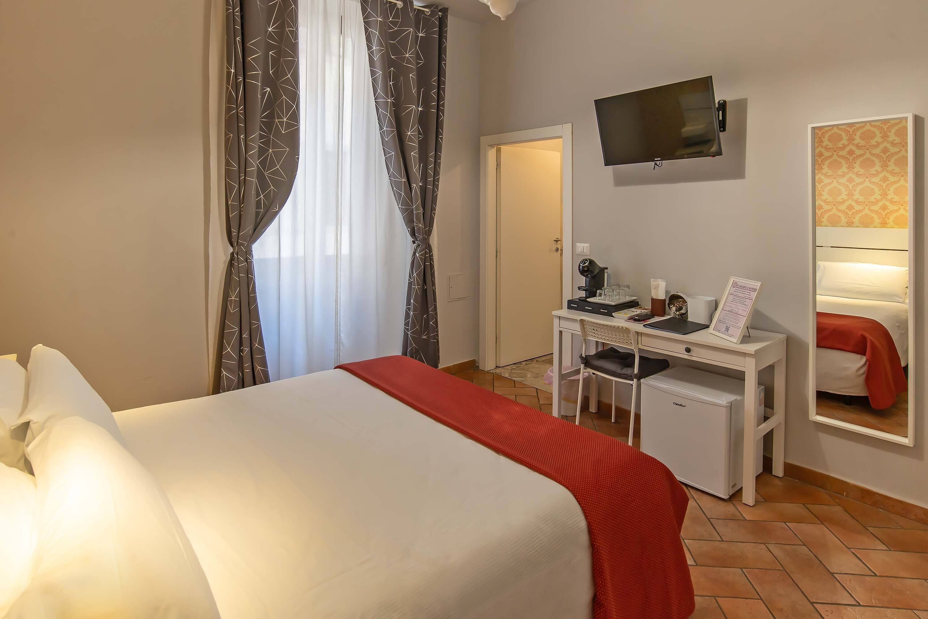Une chambre d’hôtel équipée d’un lit, d’un bureau, d’une télévision et d’un petit réfrigérateur.