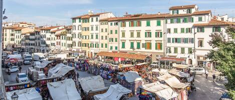 A bustling street market with various stalls and buildings in the background.