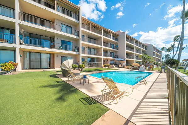 A hotel with a swimming pool, multiple balconies, and a well-maintained lawn.