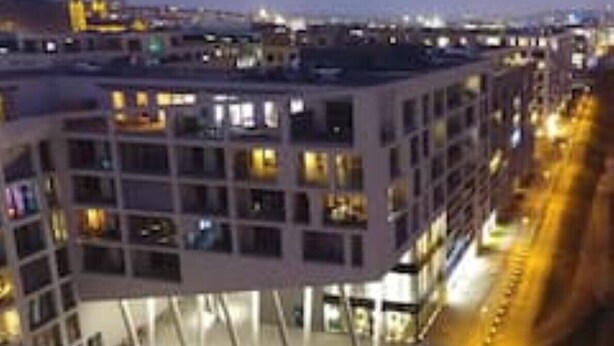 Un edificio moderno con varios pisos y balcones, que presenta una fachada estructurada y en forma de cuadrícula.