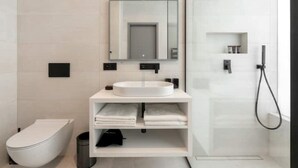 Un baño moderno con inodoro, lavabo con espejo y ducha.