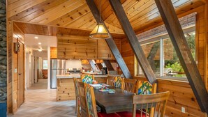 Un interior de madera con comedor, cocina y ventanas amplias.