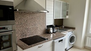 A modern kitchen with granite countertops, a built-in oven, a microwave, a toaster, and a washing machine. - Appartement Debourg Lyon 7 (Lyon)