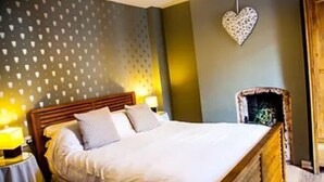 Un dormitorio con una cama, dos lámparas de noche, un adorno en forma de corazón en la pared y un cabecero de madera.