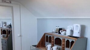 Una habitación pequeña y funcional con un aparador de madera, un refrigerador blanco y un espejo en la pared.
