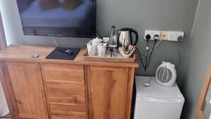 Un mueble de madera con un televisor de pantalla plana, una tetera y un pequeño electrodoméstico blanco encima.