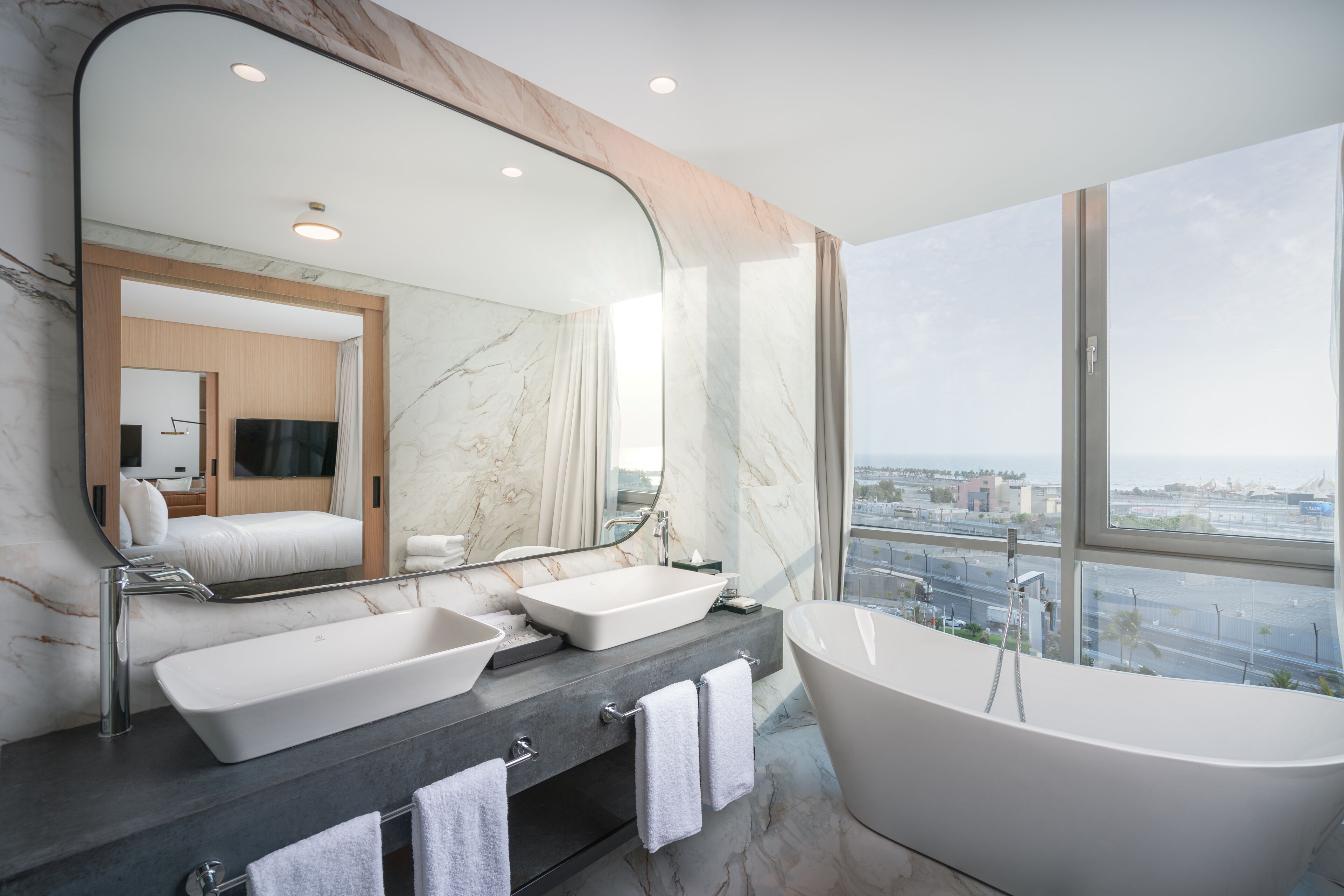 Un baño moderno con una bañera grande, dos lavamanos y un espejo amplio.