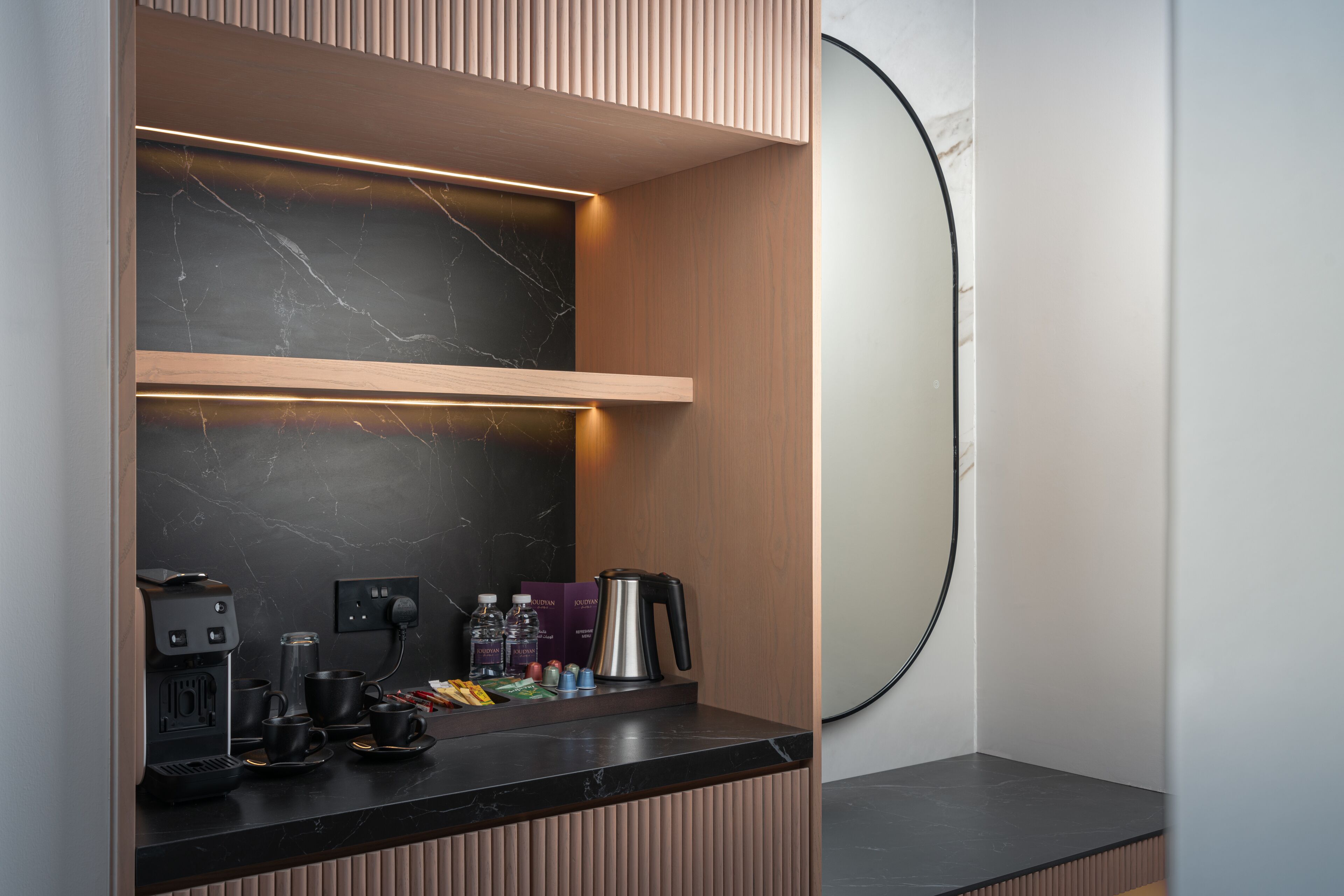 Una kitchenette moderna con salpicadero de mármol, una cafetera y un hervidor sobre la encimera.