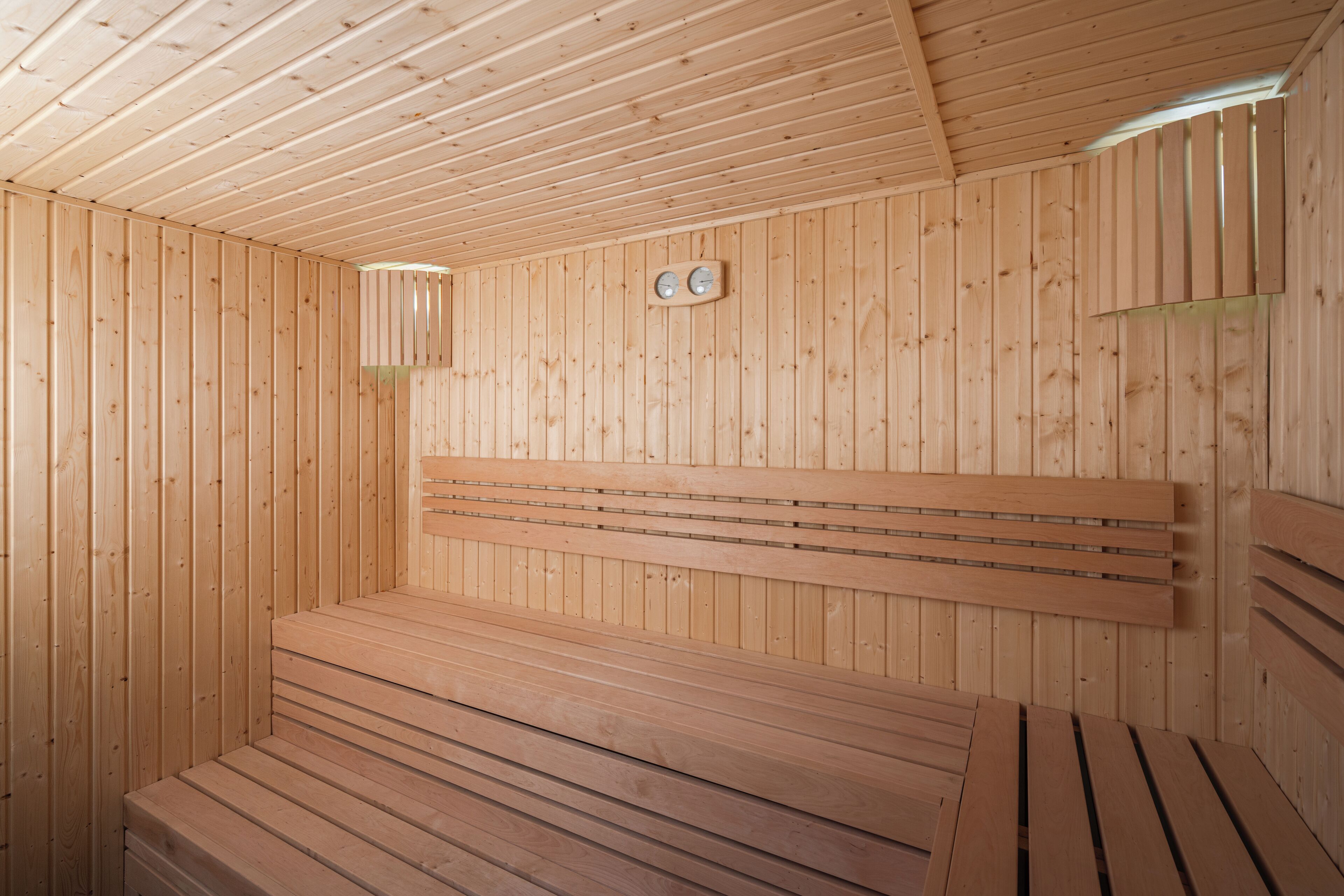 A wooden sauna with benches and a sloped ceiling.