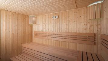 A wooden sauna with benches and a sloped ceiling.