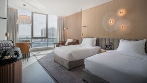 A modern hotel room with two beds, a desk, and a large window offering a city view. - Joudyan Jeddah Red Sea Mall (Jeddah)