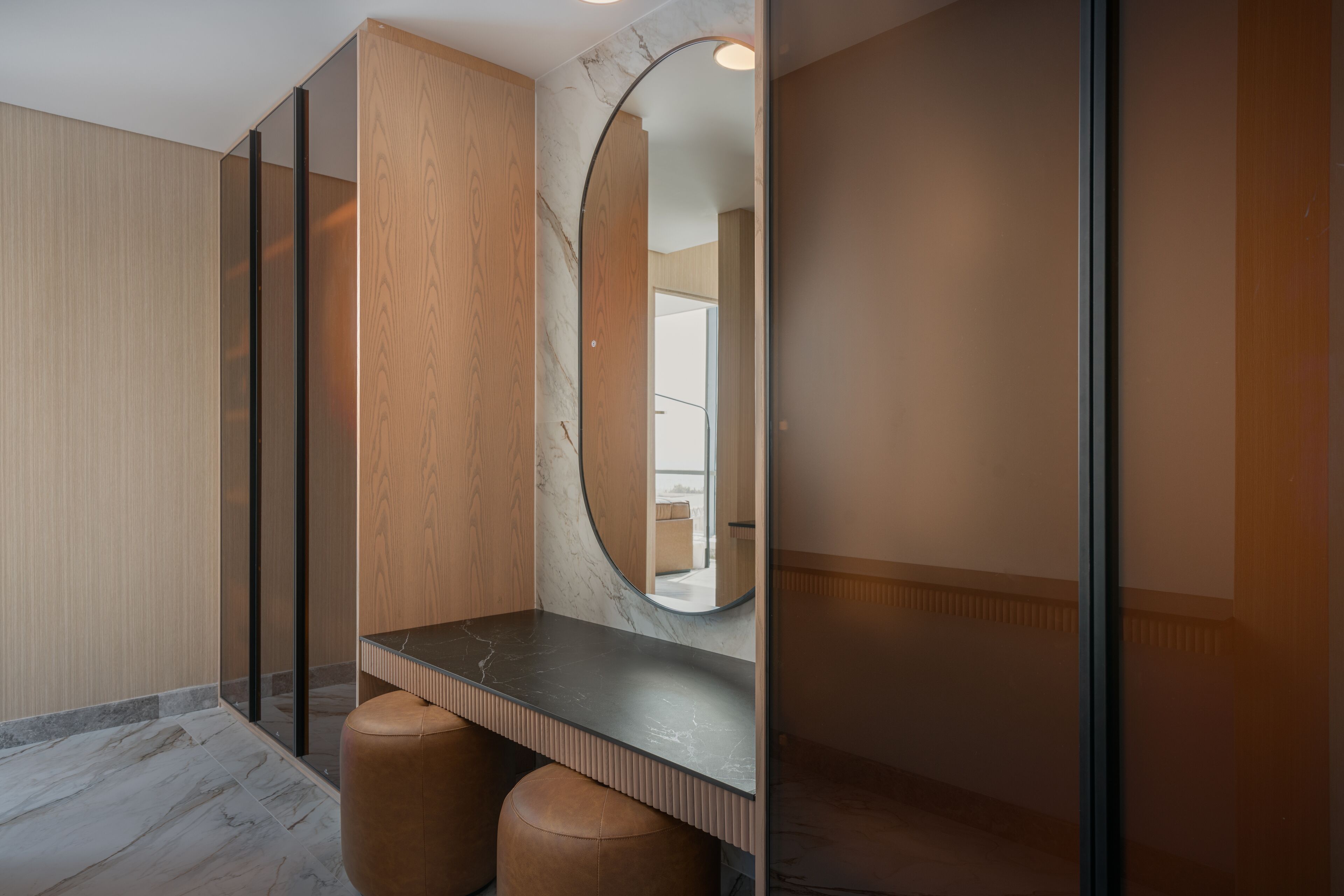 Un bagno moderno con un mobile contenitore in legno, un piano di lavoro in marmo e un ampio specchio.