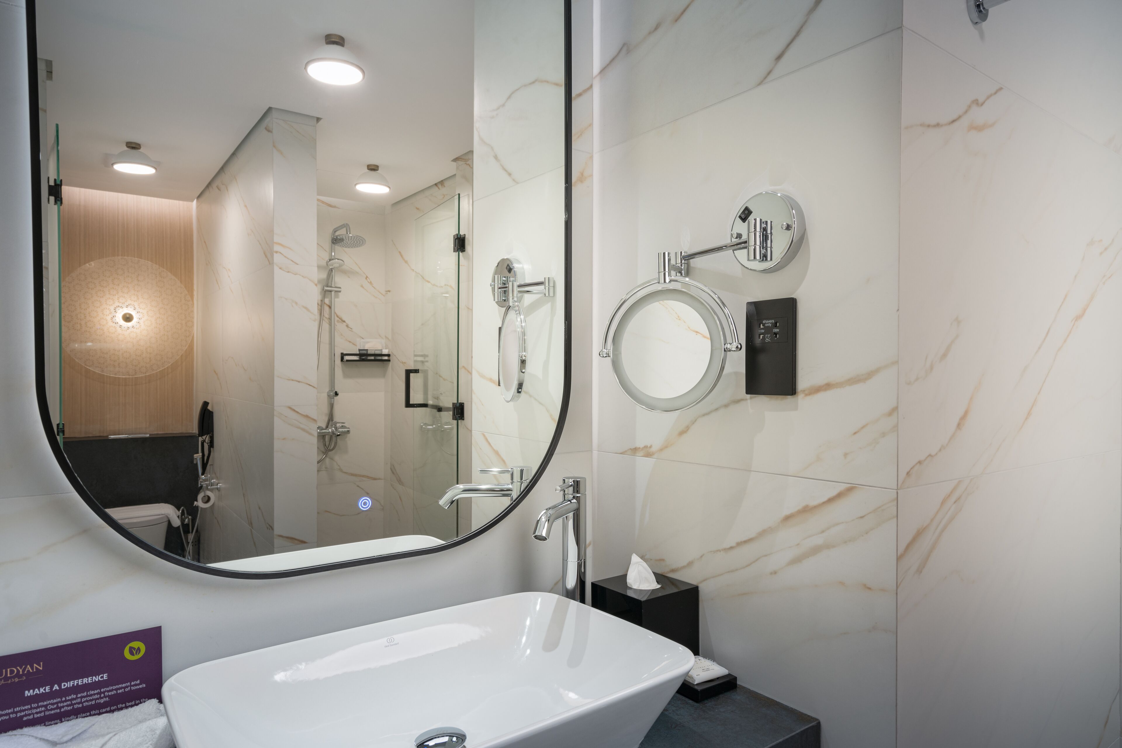 Un baño moderno con un espejo ovalado grande, una bañera independiente y un cabezal de ducha de mano.