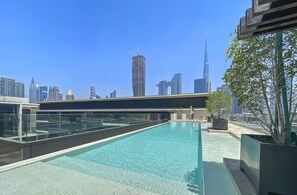 A rooftop pool with a city skyline in the background, including a prominent skyscraper. - WelHome - Luxury Living in Dubai's  City Walk Building 5 (Dubai)