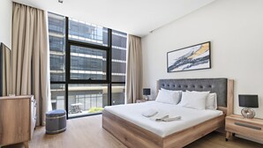 Une chambre d’hôtel moderne dotée d’un grand lit, offrant une vue sur la ville et présentant une décoration minimaliste.